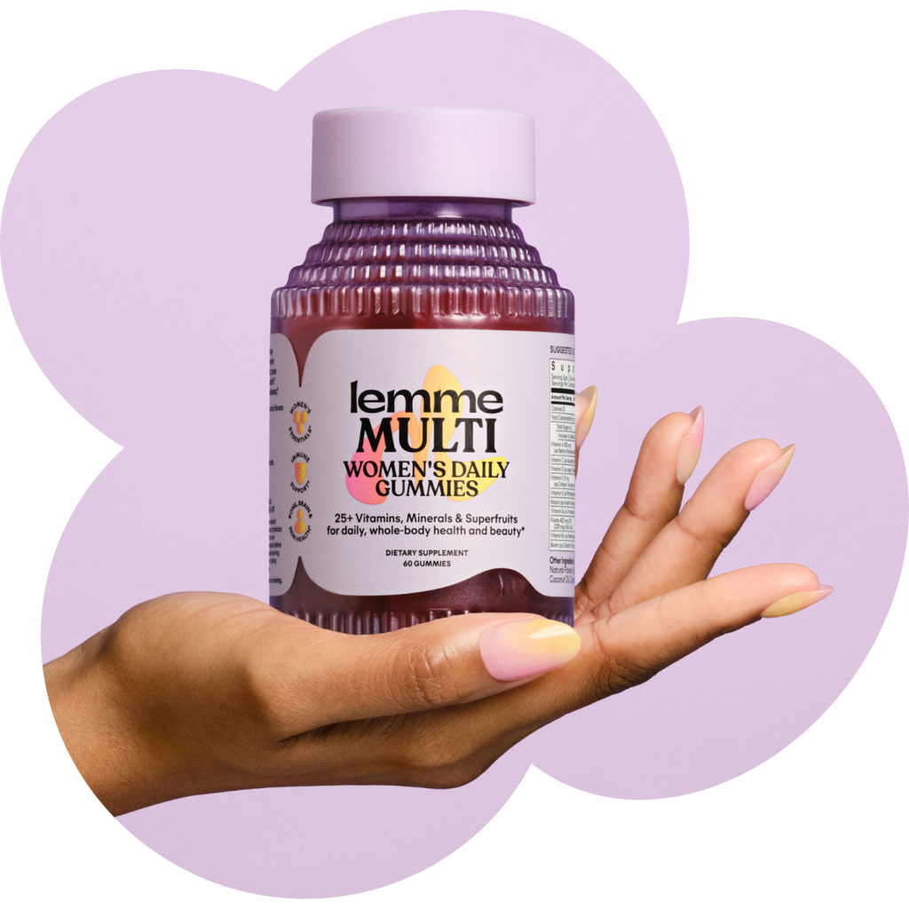 Hand holding a bottle of 'lemme MULTI' women's daily gummies against a purple heart-shaped background